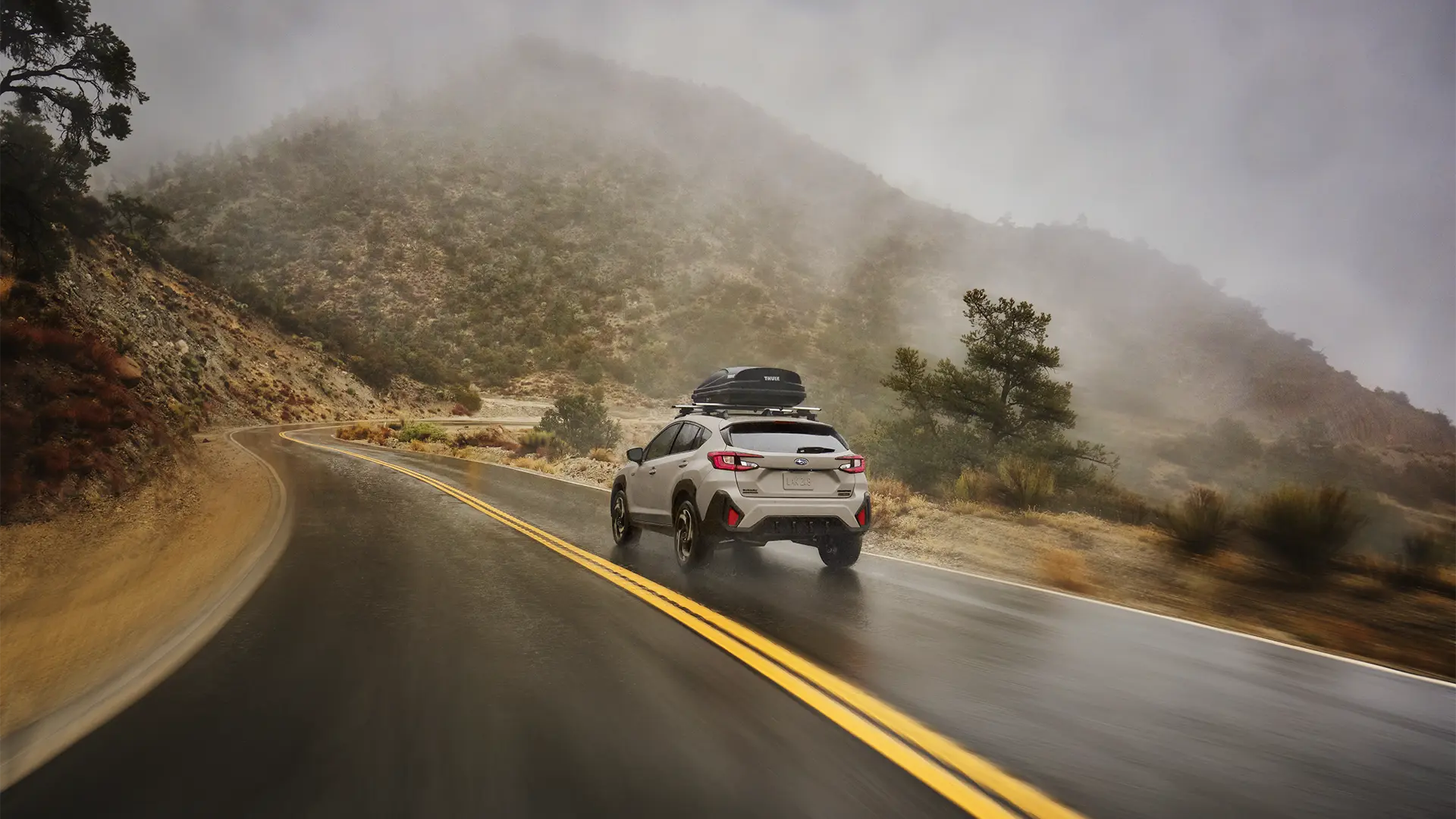Crosstrek Hybrid driving on rainy road.